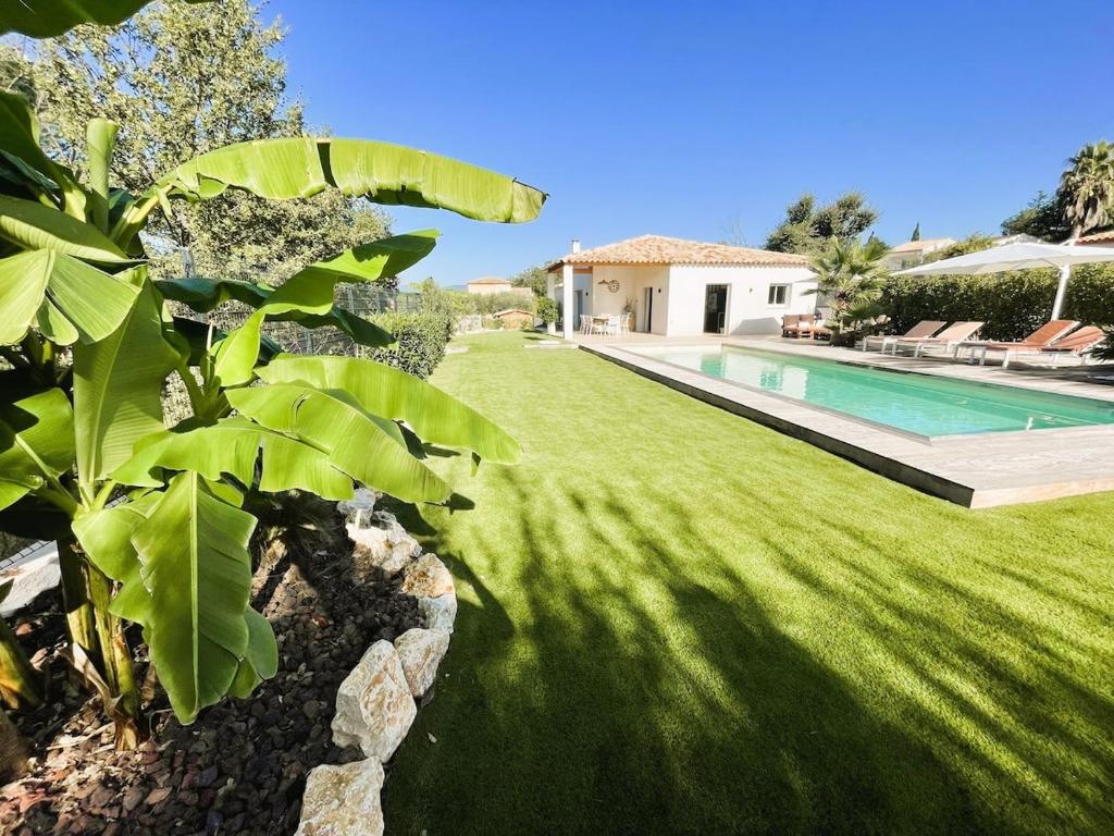 une cour avec une piscine et de l'herbe verte dans l'établissement Villa, à Roquebrune-sur Argens
