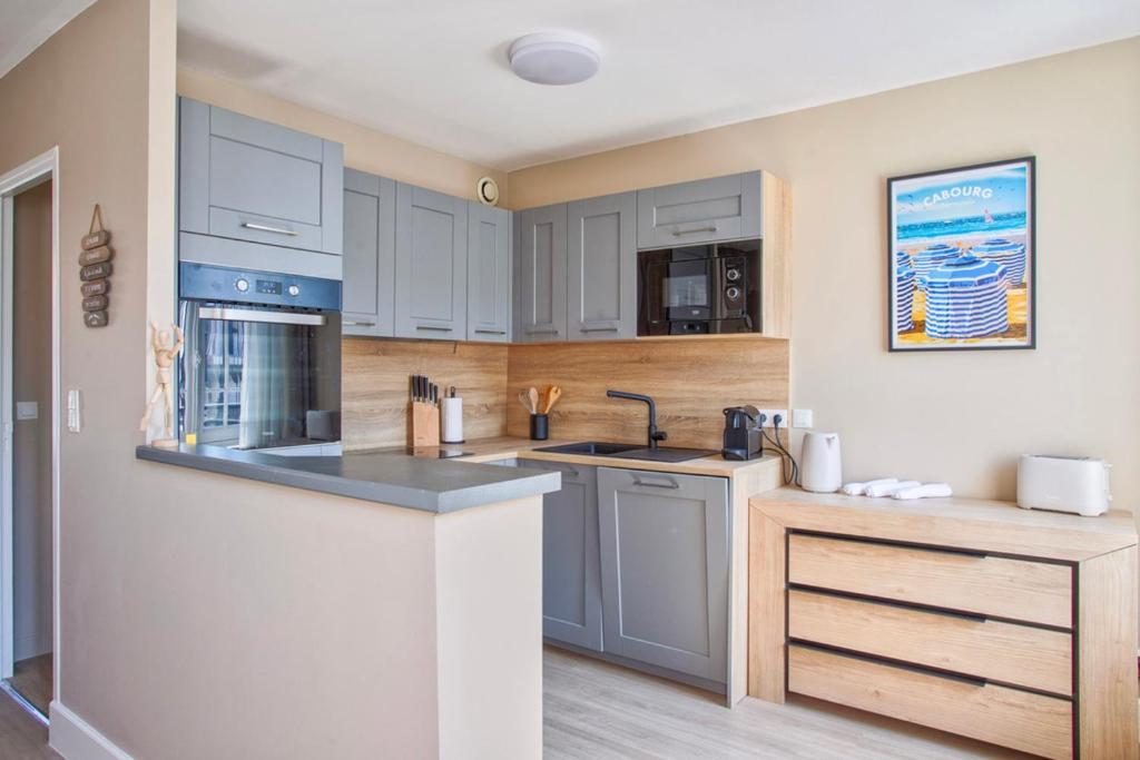 une cuisine avec des armoires blanches et des appareils bleus dans l'établissement de Funés, à Trouville-sur-Mer