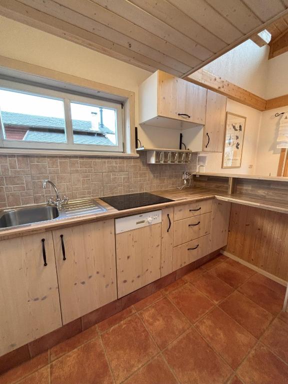 a kitchen with white cabinets and a sink and a window at Familienchalets am Millstätter See in Rothenthurn