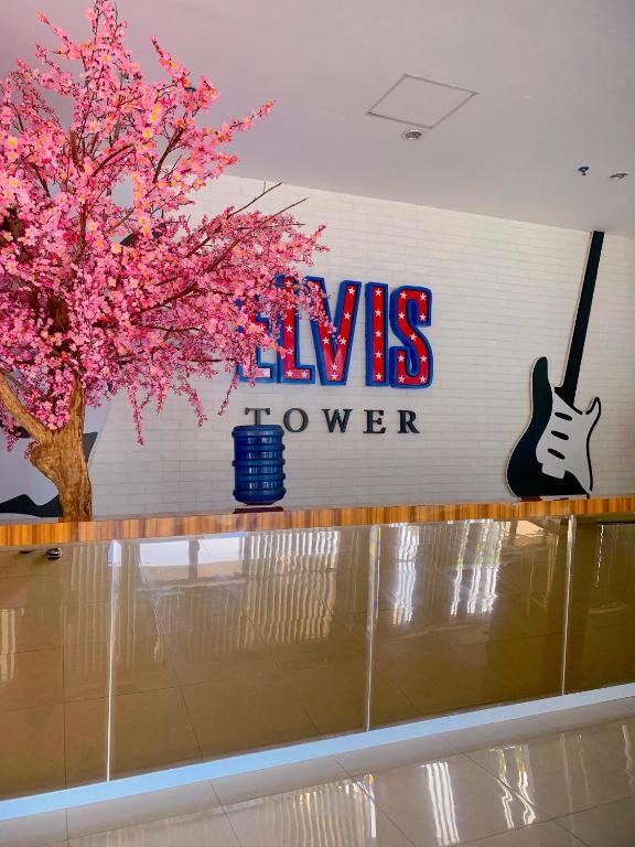 a sign on a wall with a tree with pink flowers at Apartment Elvis Tower Cikarang in Pegadungan