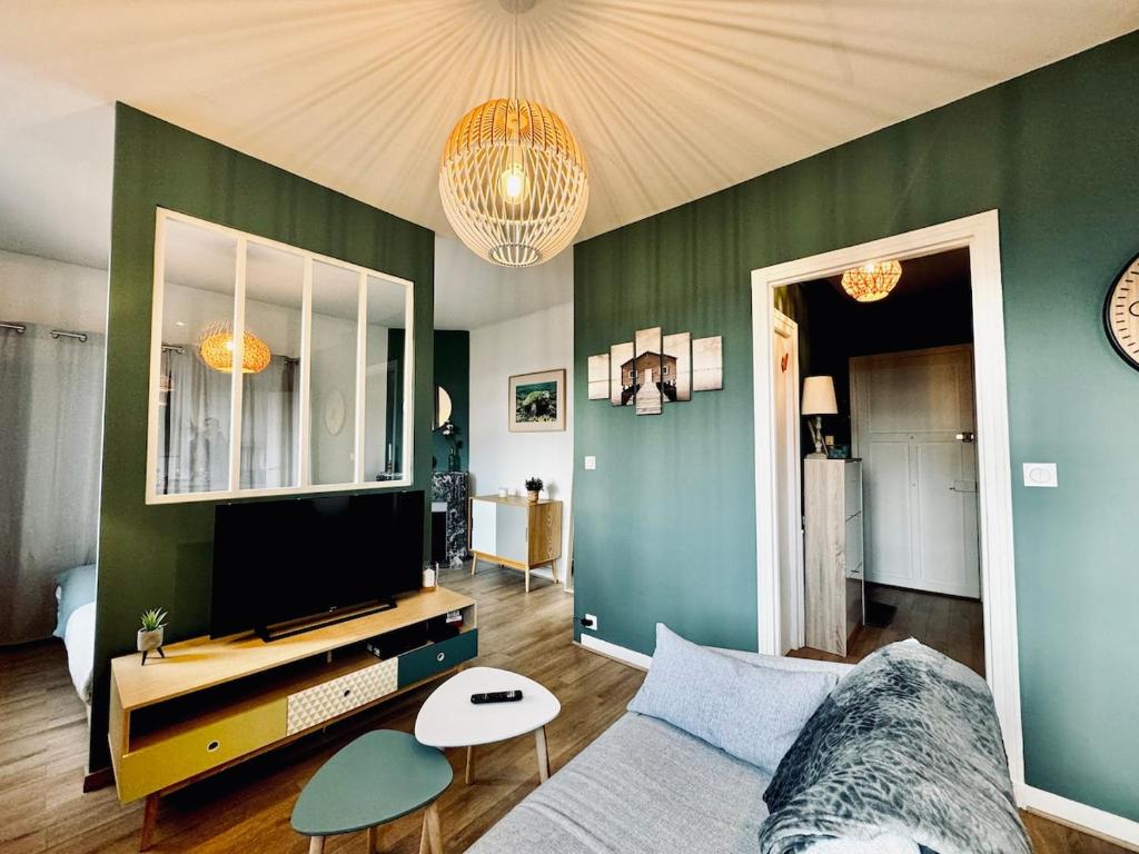 un salon avec un canapé et une télévision à écran plat dans l'établissement L ESCALE, grand studio près de la gare, à Rennes