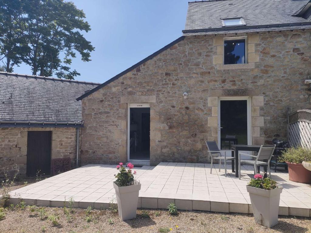 Cette maison en briques dispose d'une terrasse avec une table et des chaises. dans l'établissement Ref 018 2 Maison pour 2 personnes avec grand jardin partagé, à Arzon
