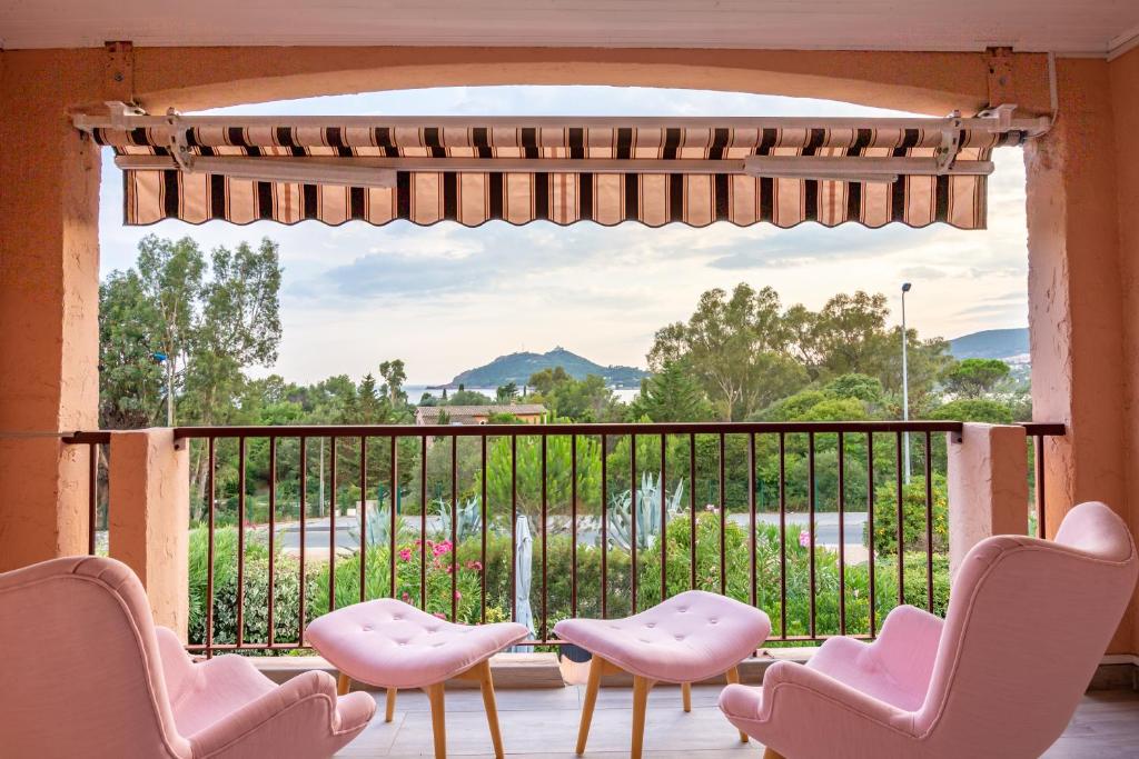 d'un balcon avec des chaises roses et une grande fenêtre. dans l'établissement Duplex Agay-Plage, à Saint-Raphaël