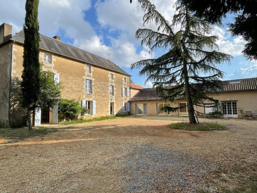a large brick building with a tree in front of it at Gîte Le Grand Bourneau - Charme & Fraîcheur - 20 min Futuroscope in Nouaillé-Maupertuis