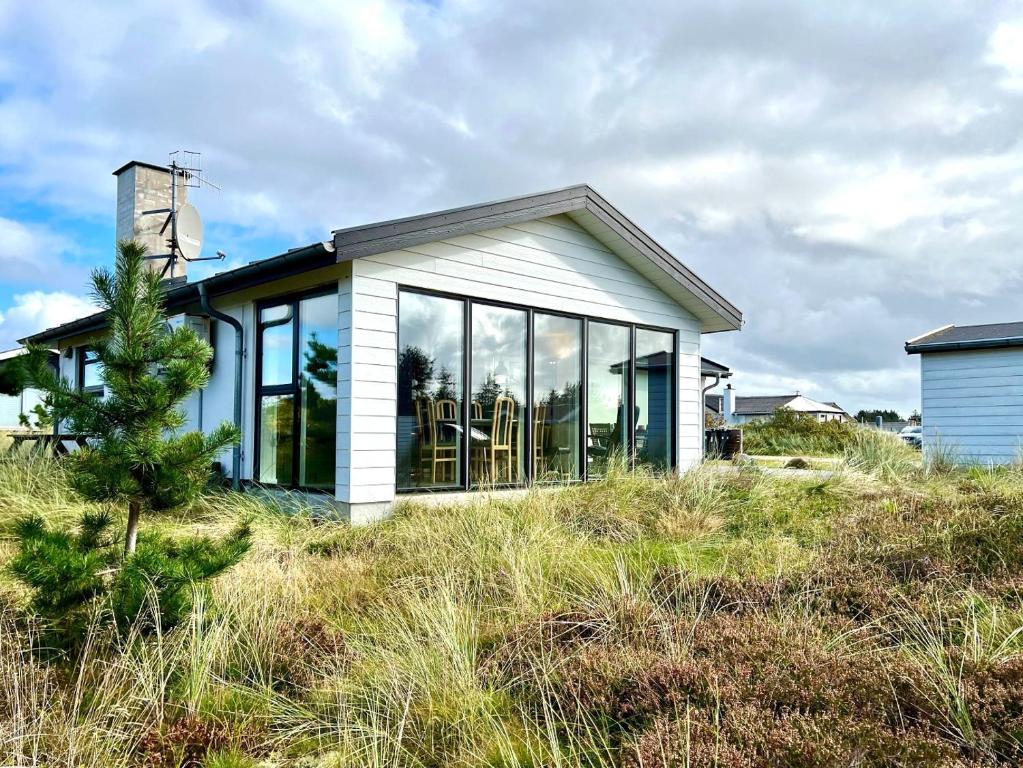 a small house with large glass windows on a hill at Hyggeligt feriehus in Thisted