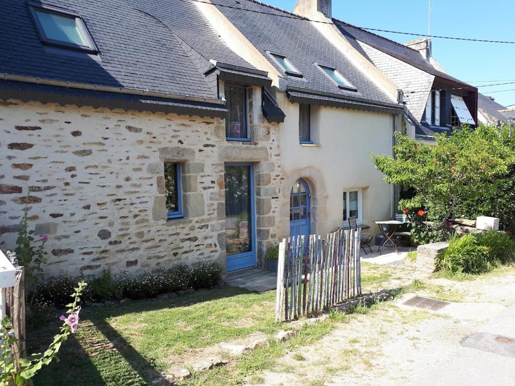 une maison en pierre avec une porte bleue et une clôture dans l'établissement Maison de charme entre Golfe du Morbihan et Océan, à Sarzeau