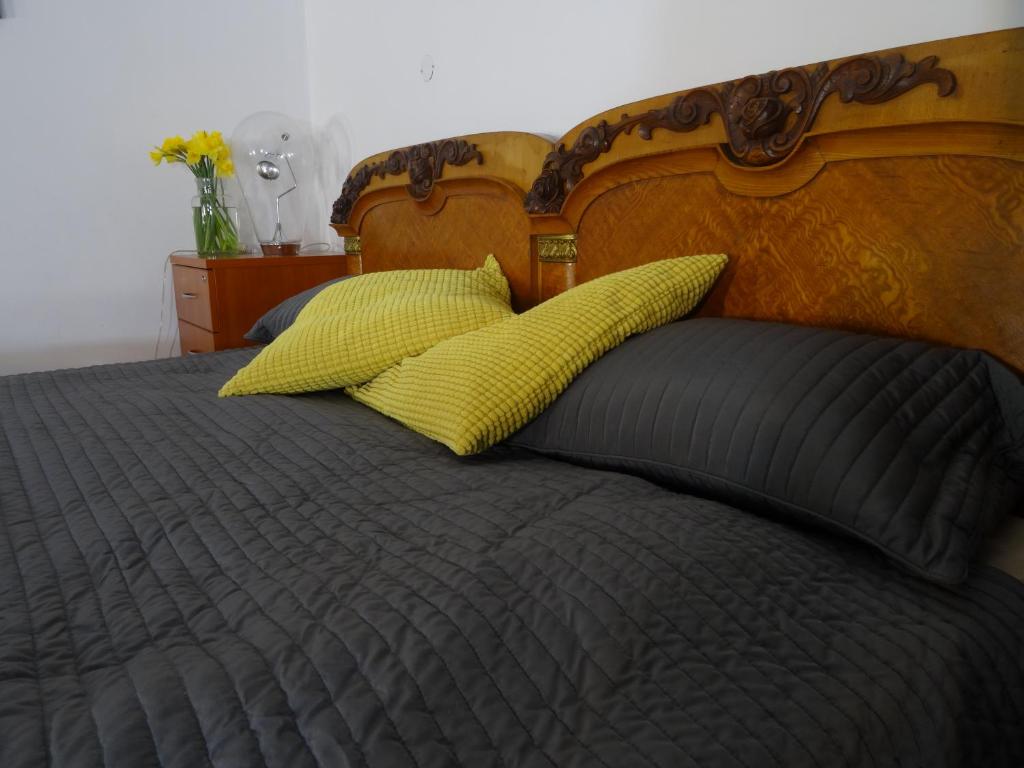 a bed with two yellow pillows and a wooden headboard at Nice Place in Krakow