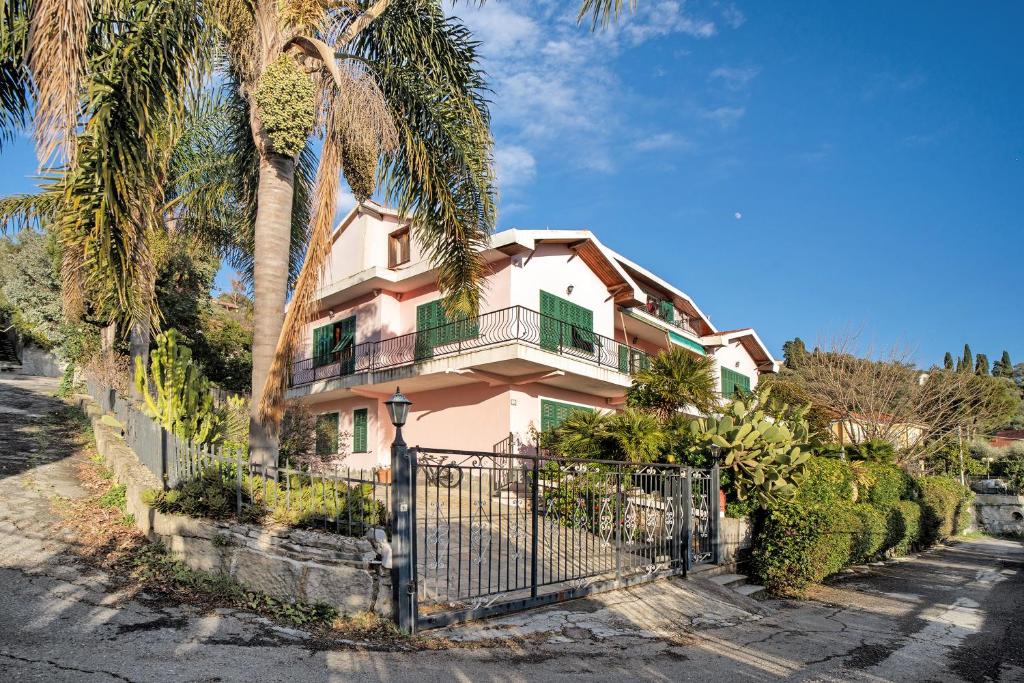 ein rosafarbenes Haus mit einem Zaun und Palmen in der Unterkunft Villa Bella Vista in Imperia