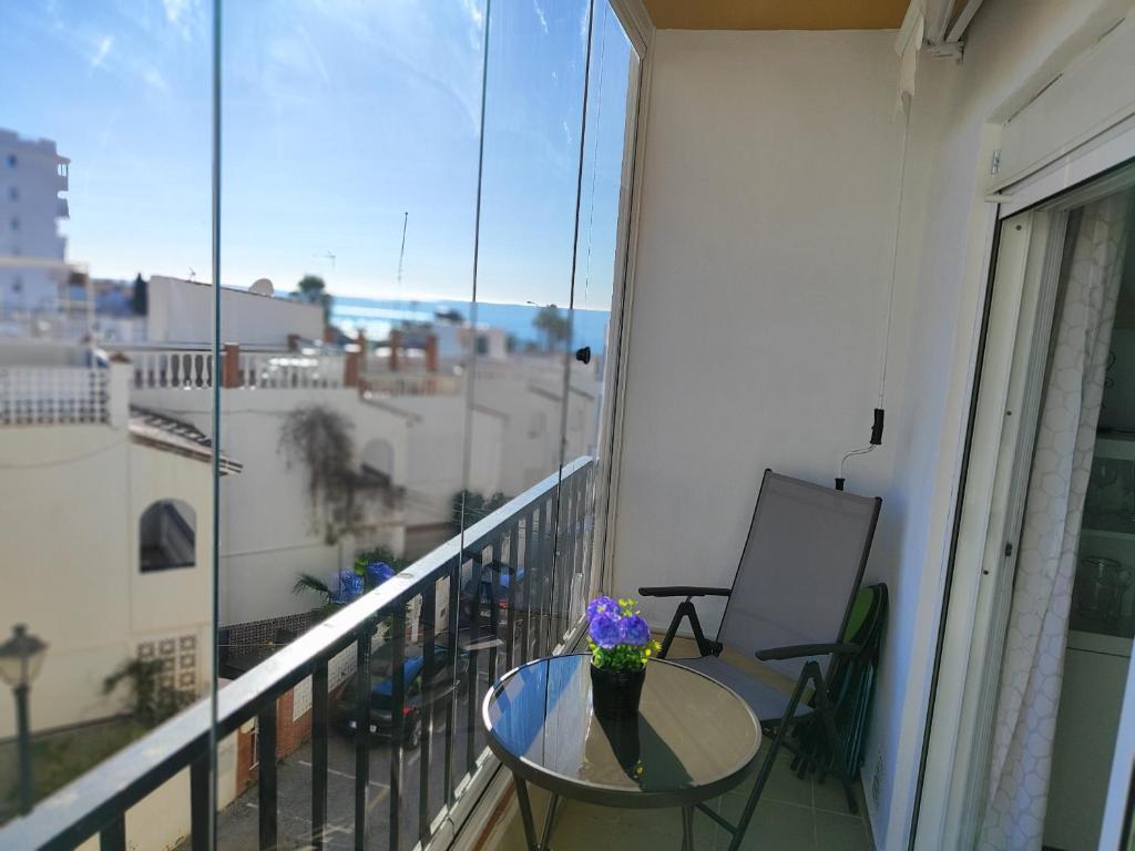 balkon ze stołem z wazonem kwiatów w obiekcie Edf Albaida II 2D - Eurosur w mieście Nerja