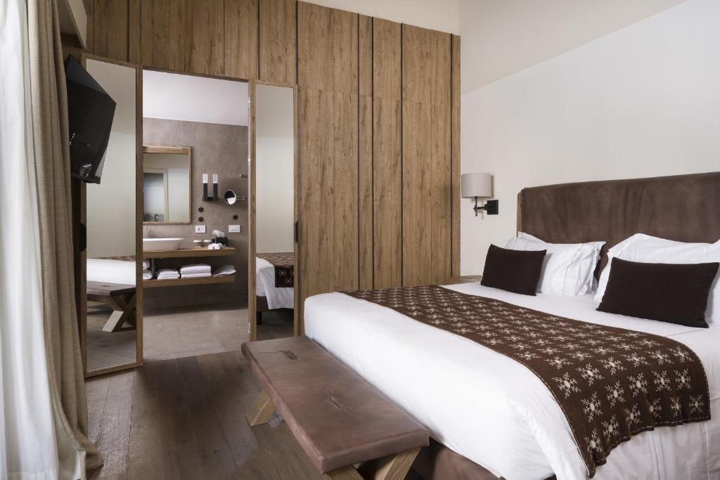 Pokój hotelowy z dużym łóżkiem i lustrem w obiekcie Grand Hotel Courmayeur Mont Blanc, by R Collection Hotels w mieście Courmayeur