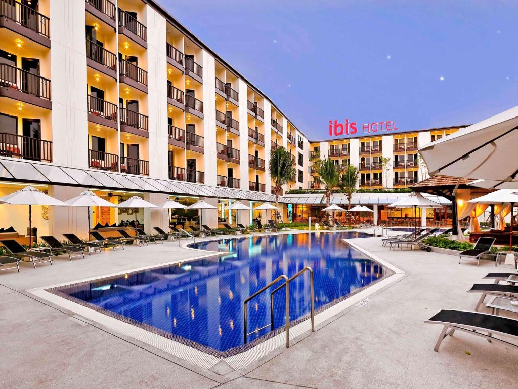 a hotel with a swimming pool in front of a building at Ibis Phuket Kata in Kata Beach