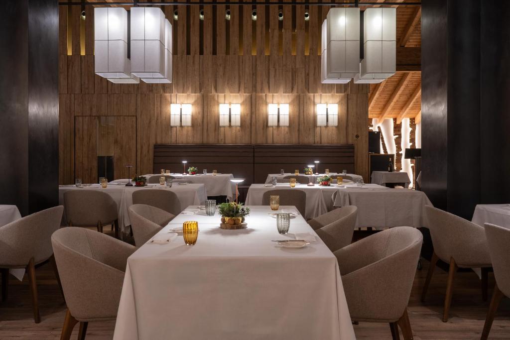 restauracja z białymi stołami, krzesłami i oświetleniem w obiekcie Grand Hotel Courmayeur Mont Blanc, by R Collection Hotels w mieście Courmayeur