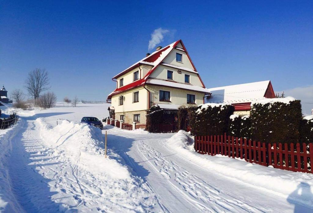 a house is covered in snow with a fence at Agroturystyka Pod Dzwonnicą - Babia Góra in Zubrzyca Dolna