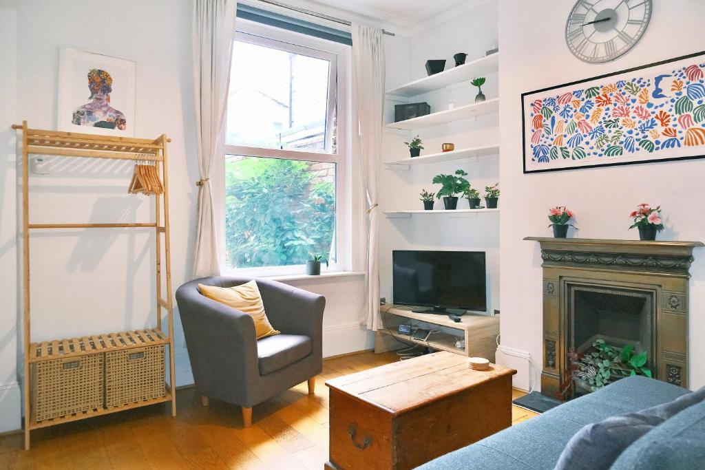 a living room with a fireplace and a chair and a television at Artsy & bright Hammersmith London 1b1b, up to 4 people in London