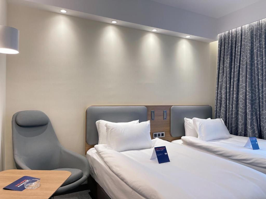 a room with two beds and a table and chairs at Holiday Inn Express - Ankara - Airport by IHG in Ankara