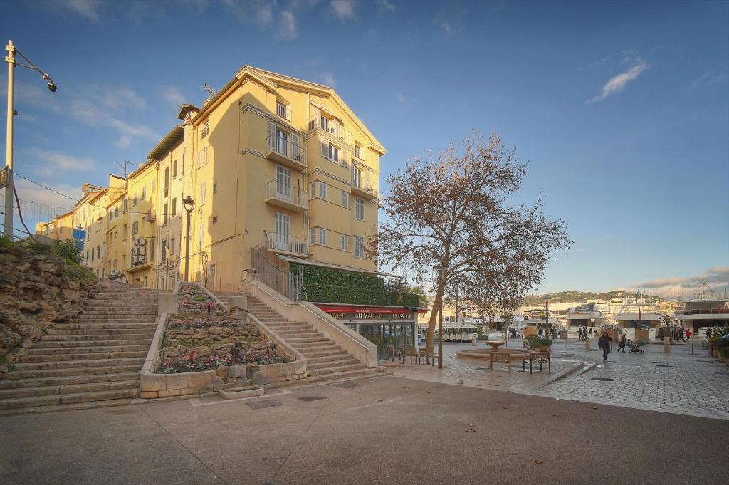 un grand bâtiment jaune avec des escaliers en face de celui-ci dans l'établissement Immogroom - T2 - AC - Suquet, à Cannes
