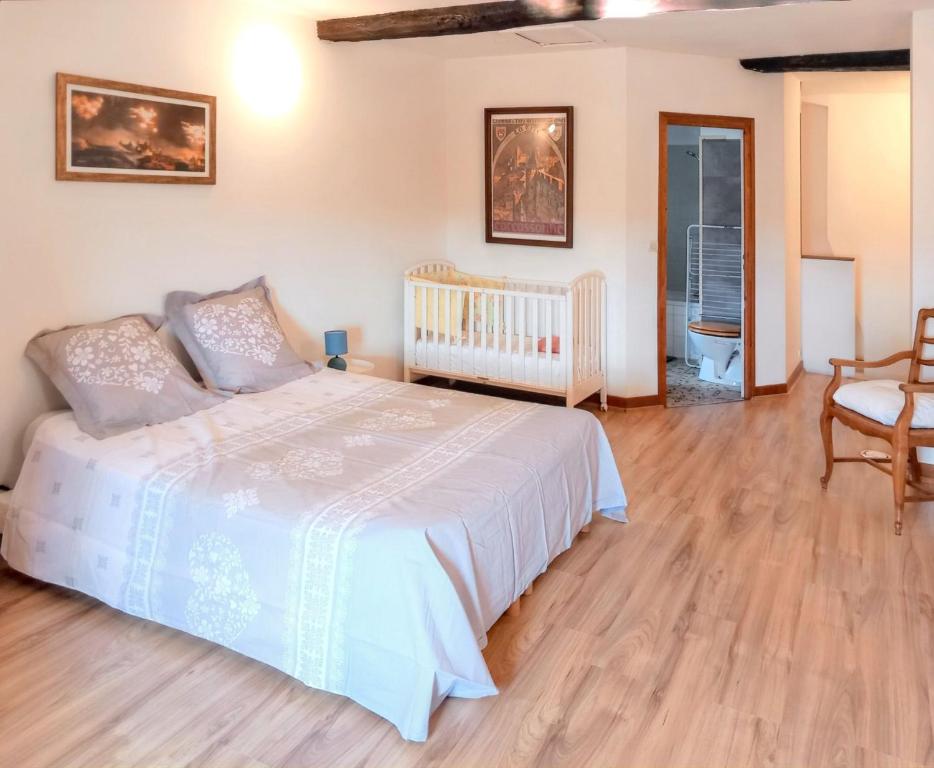 a bedroom with a white bed and a chair at Maison Renaissance avec vue imprenable sur Caunes-Minervois in Caunes-Minervois
