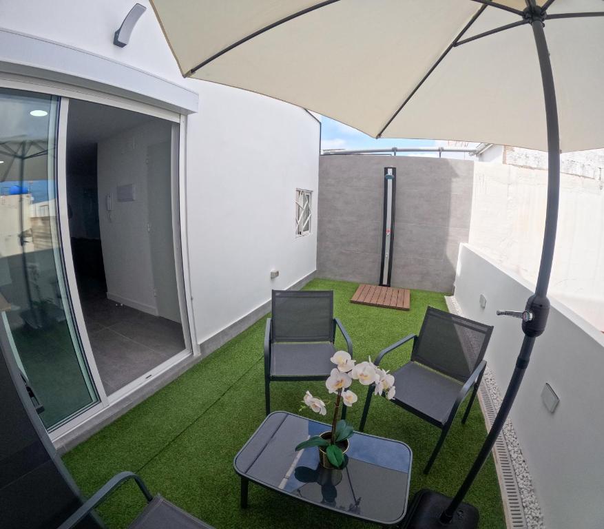 大加那利岛拉斯帕尔马斯Violeta Suite的天井配有两把椅子和一张桌子及遮阳伞