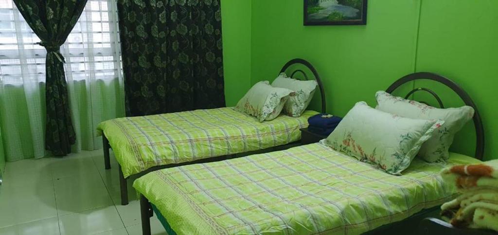 two beds in a room with green walls at Homestay Shah Alam in Shah Alam