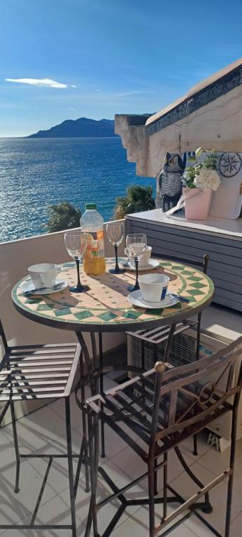 Una mesa y sillas en un balcón con vista al mar. en Ciel Bleu de Cannes - Appartement Vue Azur avec Piscines et Jardin, en Cannes