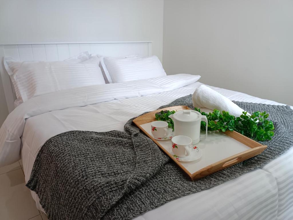 un vassoio con due tazze e due tazze su un letto di Ehsan Residence Condominium Cozy Air-Con Suite KLIA a Sepang