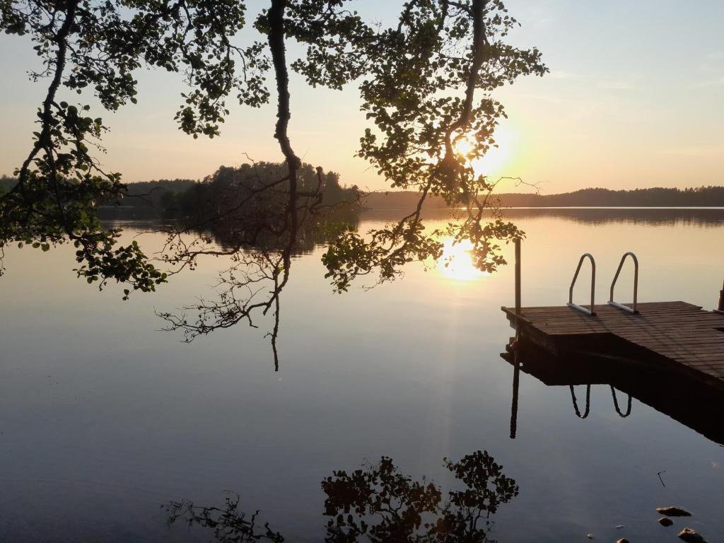 a dock on a lake with the sun setting at Källgård in Lohja