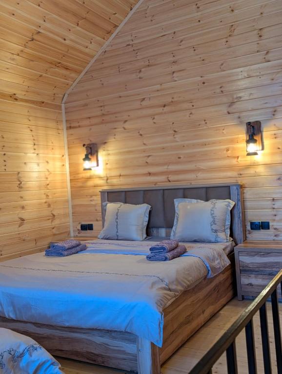 a bedroom with a large bed in a wooden wall at cottage nikolozi in Kazbegi