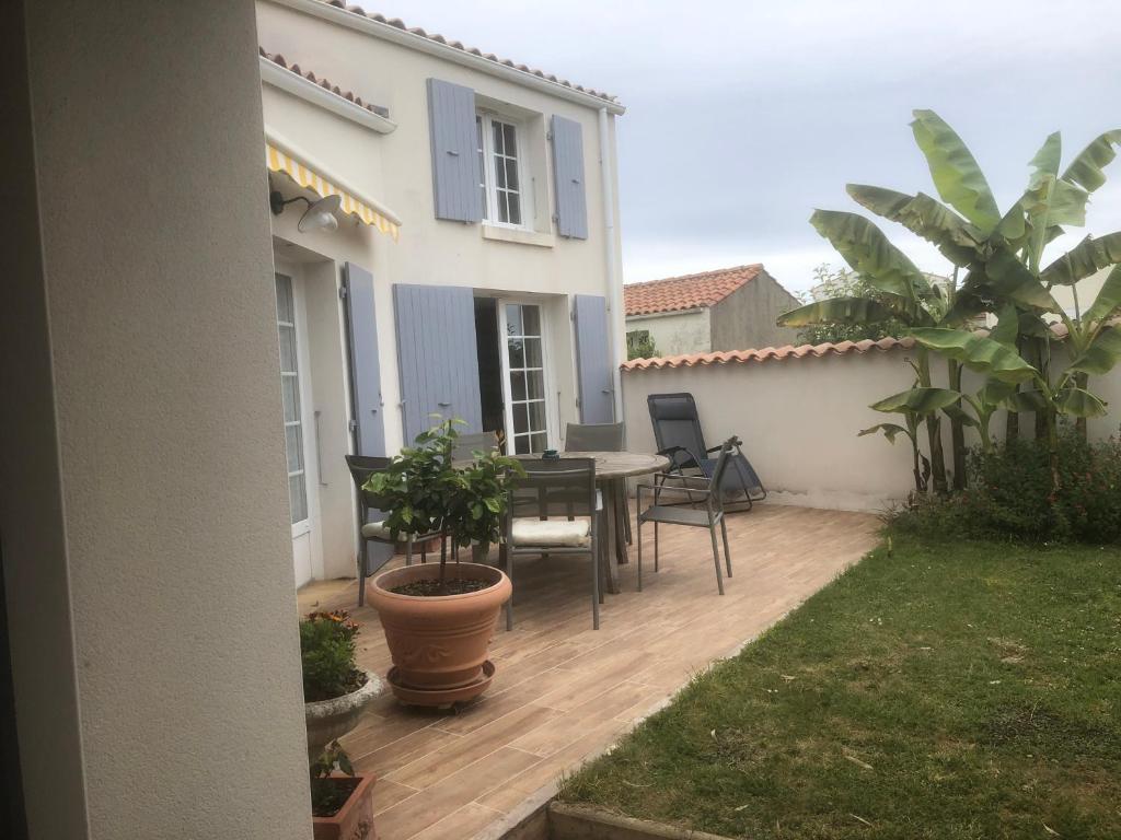 un patio avec une table et des chaises devant une maison dans l'établissement La Cocadière, au Château-dʼOléron