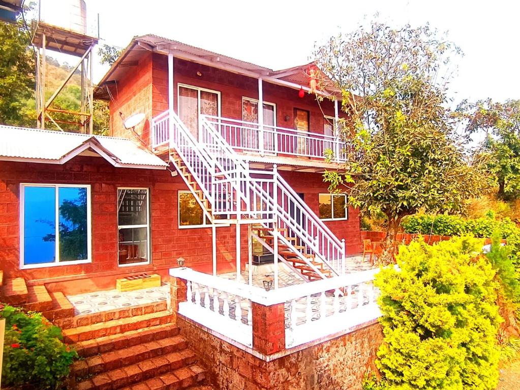 Una casa de ladrillo rojo con una escalera blanca. en ROYAL STONE VILLA, en Mahabaleshwar