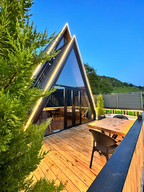 a wooden deck with a wooden table and a dining table at Vadiyebak Suit Bungalov in Akkaya