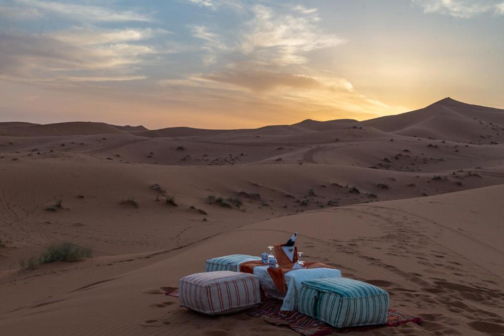 a group of chairs sitting in the sand in the desert at Desert Camp Merzouga Nights in Merzouga