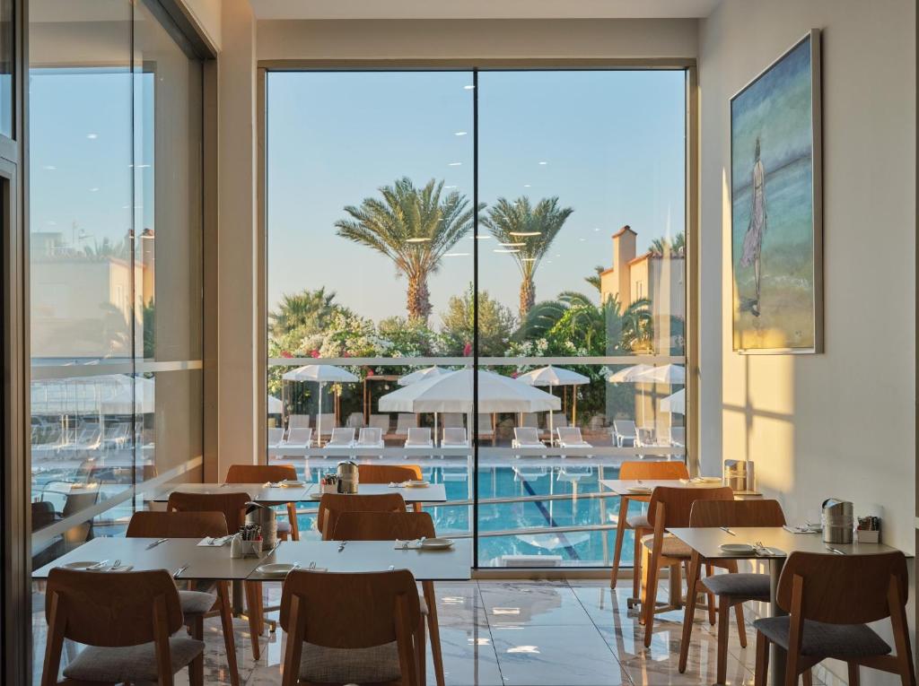 a restaurant with tables and chairs and a pool at Atlantica Sungarden Park in Ayia Napa