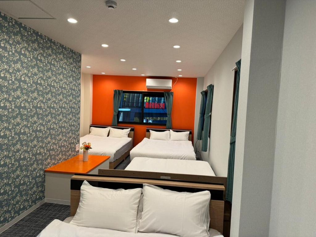 two beds in a room with orange walls at Guest House新今宫 in Osaka