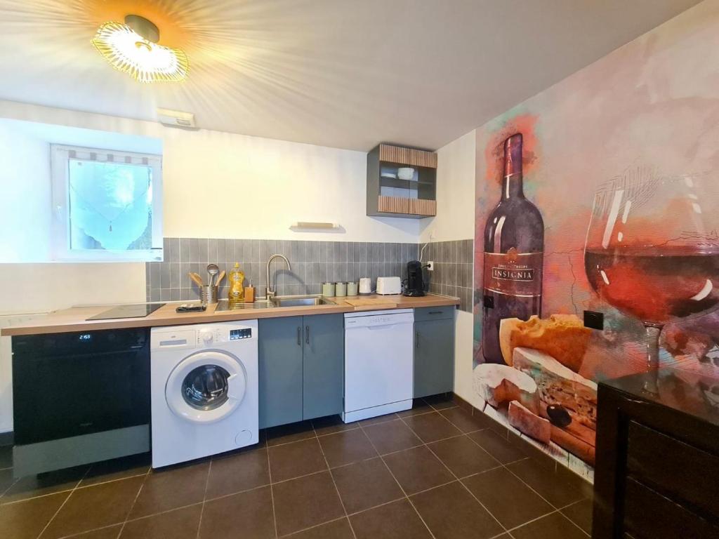 une cuisine avec un lave-linge et une peinture d'une bouteille de vin dans l'établissement Appartement familial tout équipé, à Angers