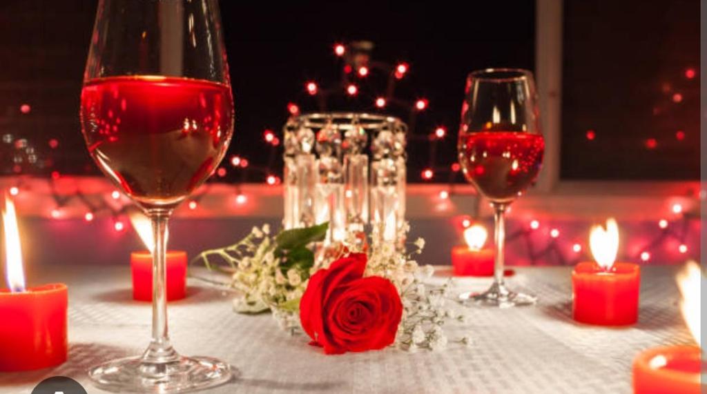 - une table avec deux verres de vin et des bougies dans l'établissement Soirée romantique LOVE ROOM, à Allez-et-Cazeneuve