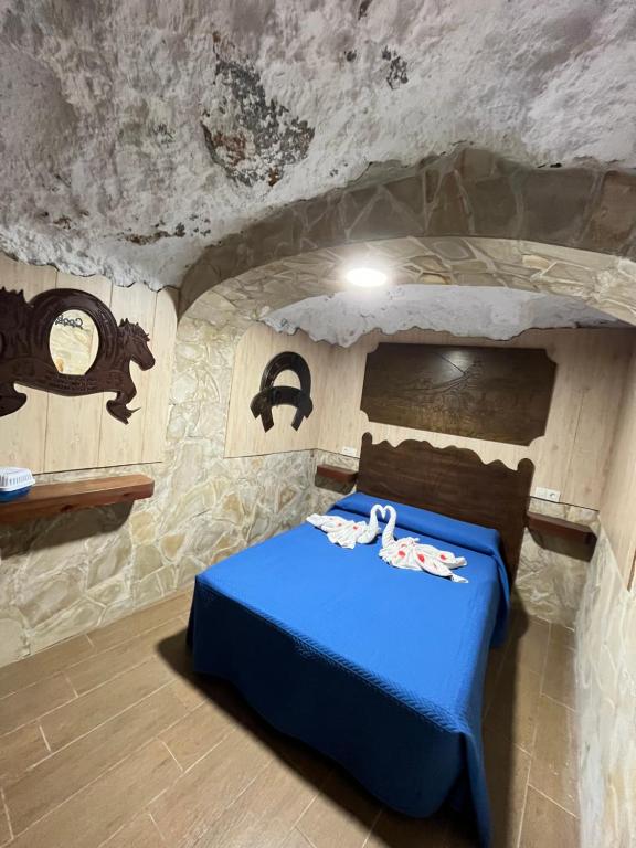 a bedroom in a cave with a blue bed at La casita medieval in Bedmar