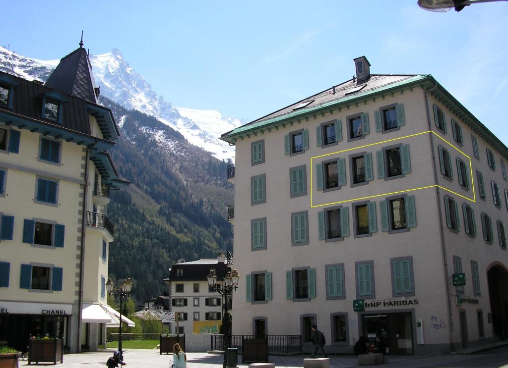 un grand bâtiment blanc avec une montagne en arrière-plan dans l'établissement Pavillon Appartement n°30, à Chamonix-Mont-Blanc