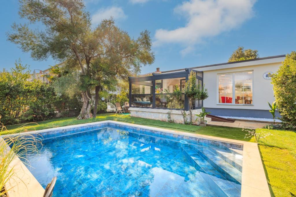a home with a swimming pool in front of a house at Jacaranda Cottage in Malinska