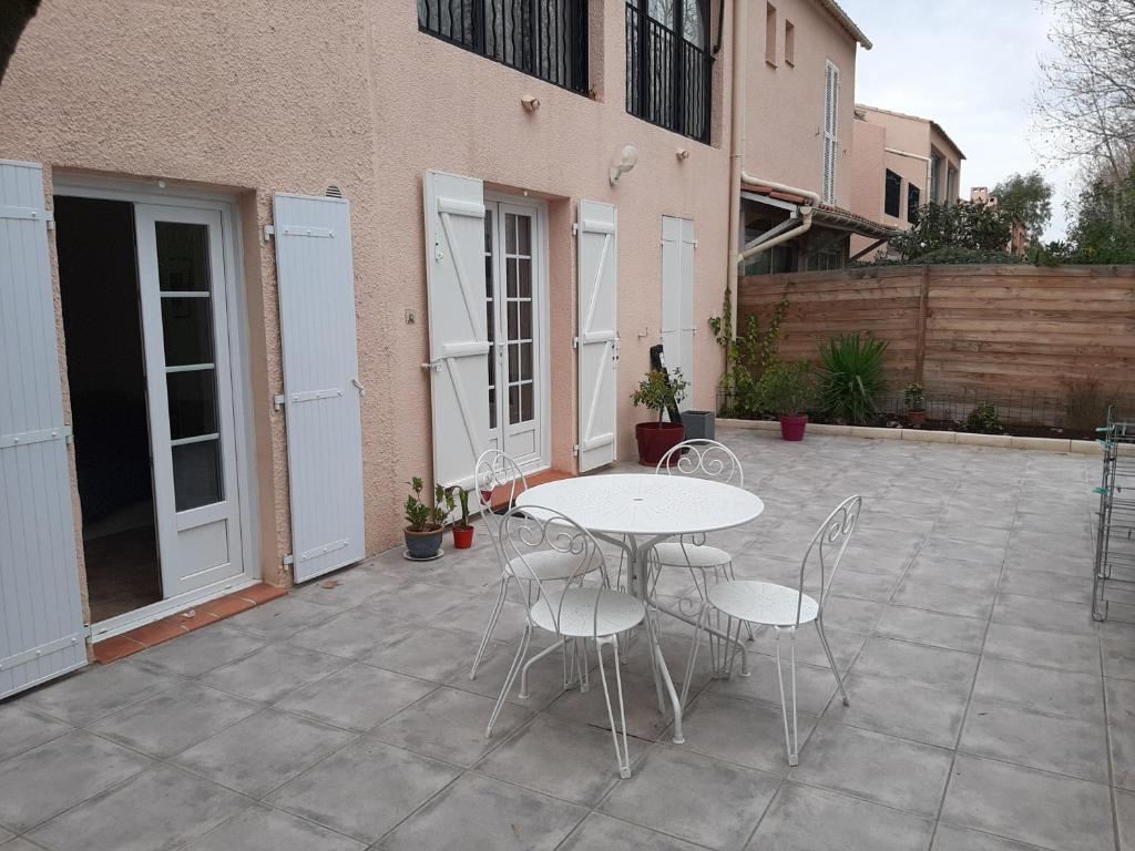 un patio avec une table et des chaises et un bâtiment dans l'établissement coin de paradis, à La Londe-les-Maures