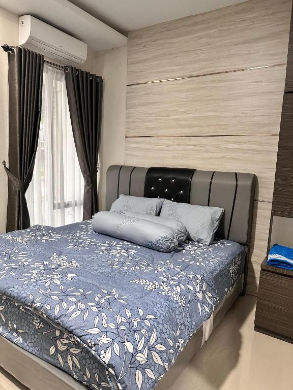 a bedroom with a bed with blue sheets and a window at Livi Guest House in Sekupang