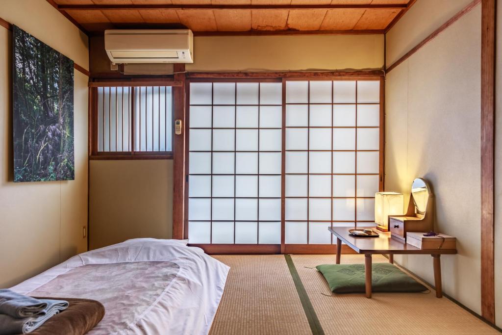 a room with a bed and a table and a window at Yadoya Hiraiwa private ryokan in Kyoto