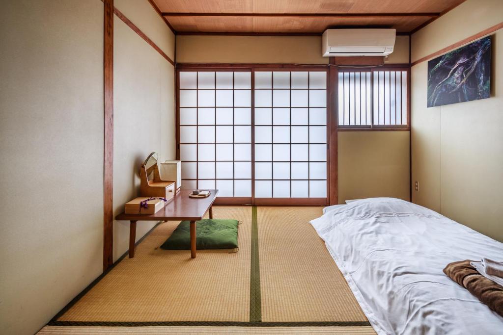 a room with a bed and a table and a window at Yadoya Hiraiwa private ryokan in Kyoto