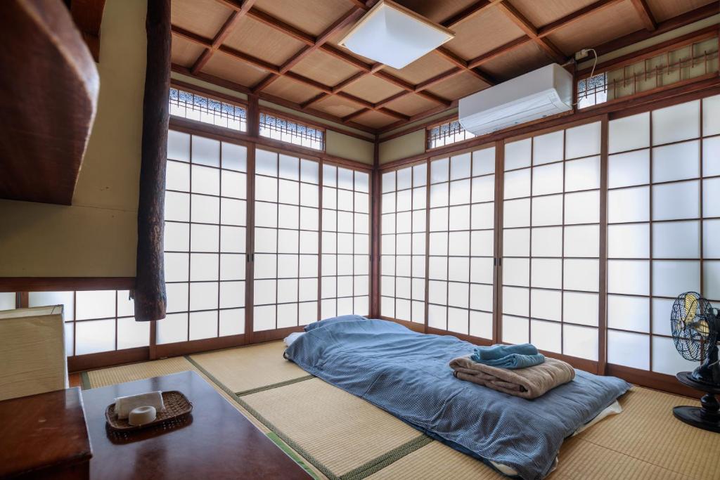 a room with a bed in a room with windows at Yadoya Hiraiwa private ryokan in Kyoto