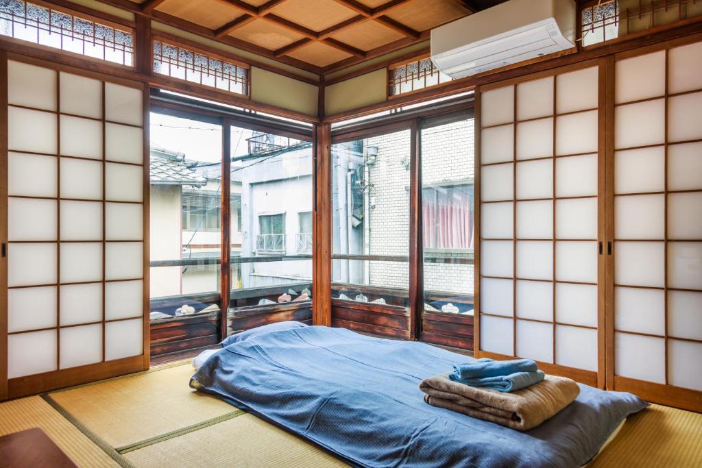 a room with a bed in a room with windows at Yadoya Hiraiwa private ryokan in Kyoto