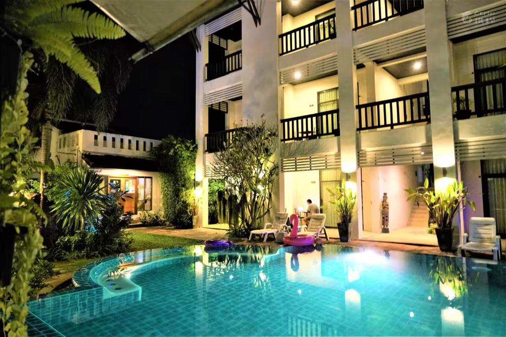 a swimming pool in front of a building at night at Monaburi Boutique Resort in Rawai Beach