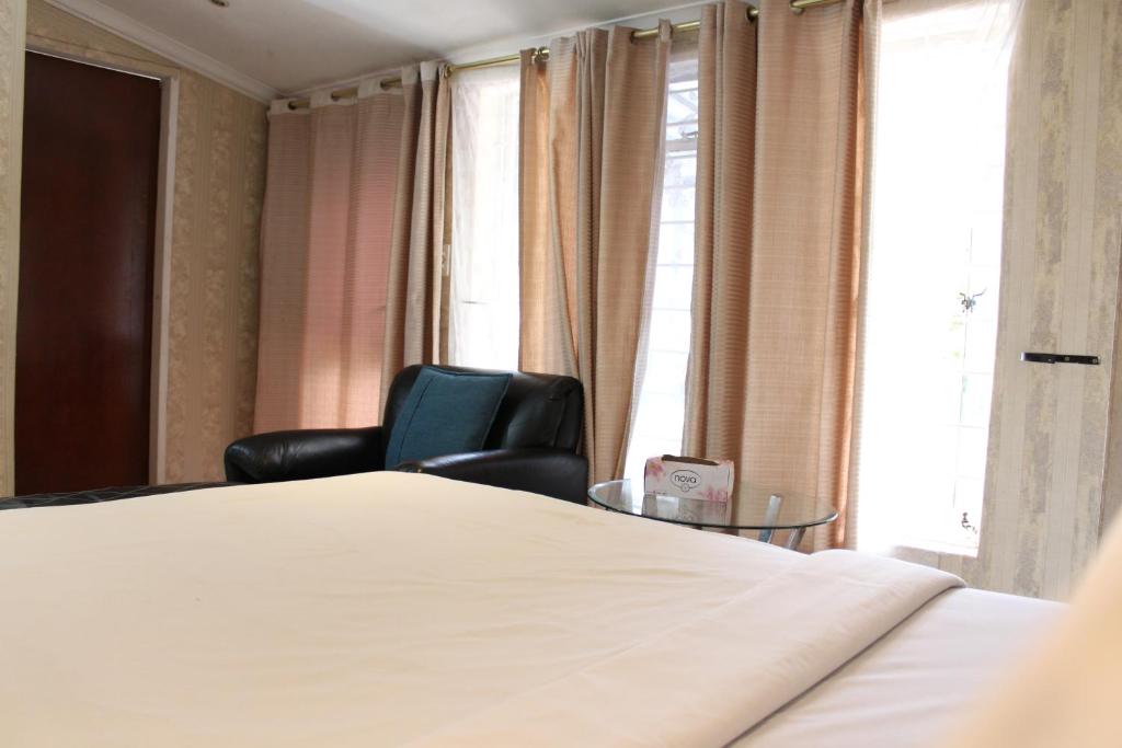 a bedroom with a bed and a chair and a window at Isabels2 Guest house in Johannesburg