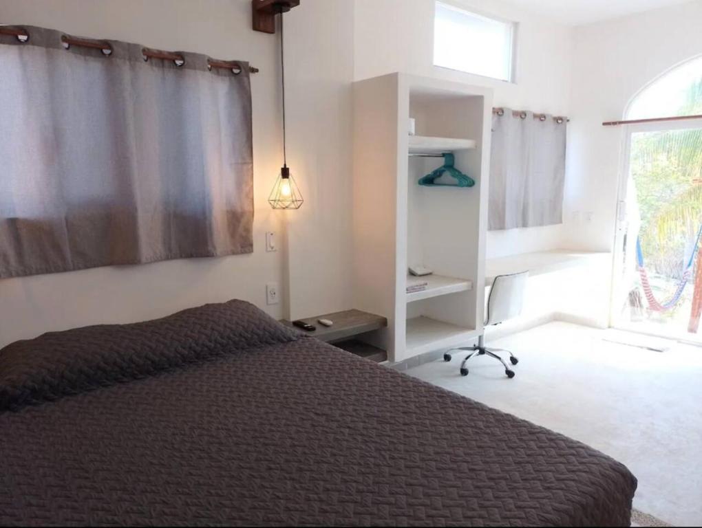 a bedroom with a bed and a window and a desk at Shaka Studio - steps to beach in Punta Mita