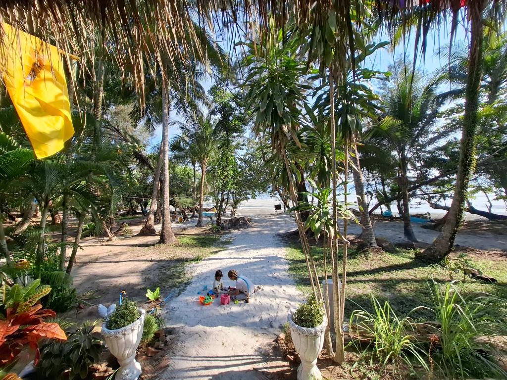 two people sitting on the beach under palm trees at Baan Suan Kayoo 1 Long beach Aow Yai in Ko Phayam