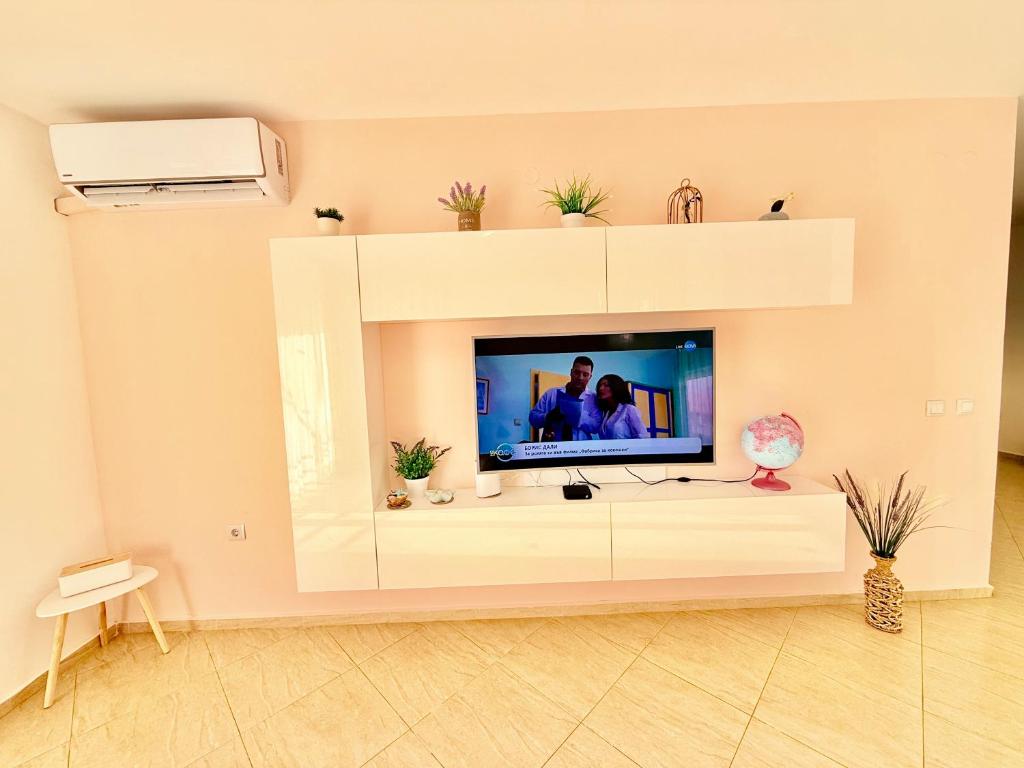 a living room with a tv in a white entertainment center at Charming 2-bed flat with pool view in Sunny Beach, Bulgaria in Sunny Beach