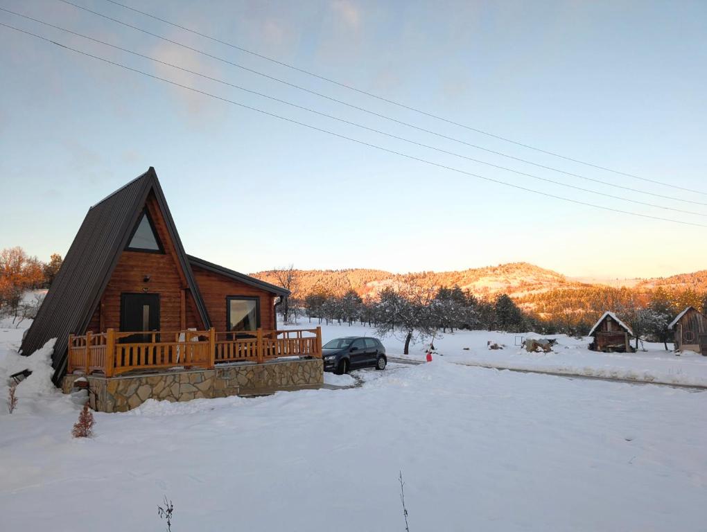 una baita di tronchi nella neve con un'auto di AA Pine vikendica za izdavanje u srcu Zapadne Srbije a Nova Varoš
